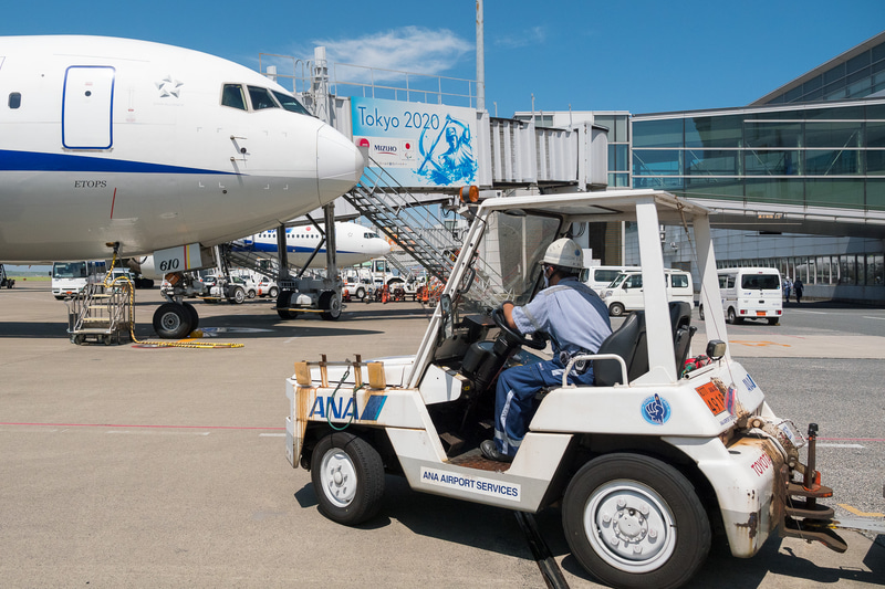 貨物を下ろす作業が進められる。ソーシャルディスタンスが確保できる屋外作業では、熱中症対策のためにマスクを外すことを推奨している