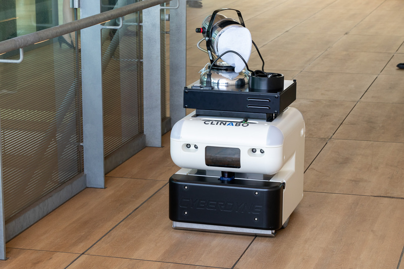 CLINABOCL02（クリナボシーエルゼロ2）。開発元は日本信号とCYBERDYNE。吸塵型清掃ロボットの上部に消毒剤噴霧機能を搭載したもので、駅での運用に必要な点字ブロックやエクスパンションの乗り越えも可能