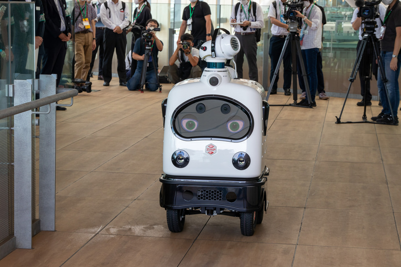 PATORO（パトロ）。開発元はZMP。パトロールと消毒作業を行なう自律移動型ロボット。複数のカメラを搭載するほか、コミュニケーション用として表情を変えられる大型ディスプレイを前面に搭載している