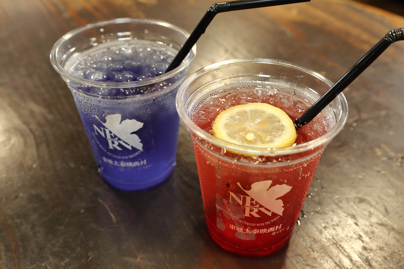 コラボドリンク2種（各600円）。赤はグレナデンソーダ（ザクロ果汁とシロップ）で、商品名は「飲めるLCL」。青はブルーハーブとも呼ばれるバタフライピーの紅茶で、商品名は「変わればいいと思うよ EVA-tea」