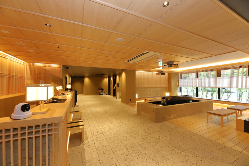 ロビーには木や石、格子を巧みに配置している。吊り天井や暖色系の照明もあり、旅館のような落ち着いた佇まいだ