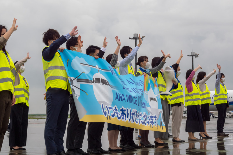 出発するNH747便を約35名のスタッフが横断幕とともにお見送り。同便は88名（幼児1名含む）を乗せ、8時54分に出発。9時3分にC滑走路から離陸し能登空港（のと里山空港）へ向かった