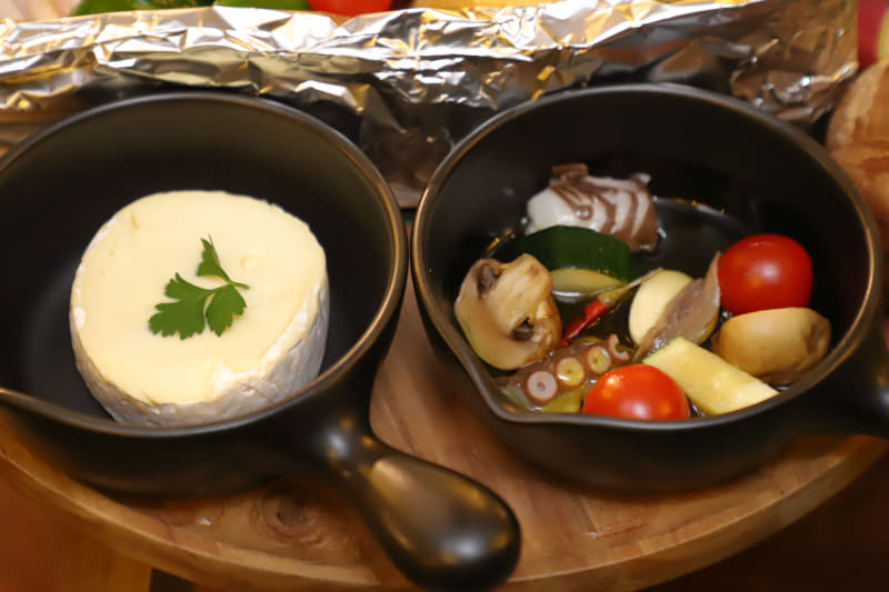 スキレットにはカマンベールチーズとアヒージョの具材がセットされている。アヒージョのタコは地元下津井産。好きなタイミングで火にかけていただこう