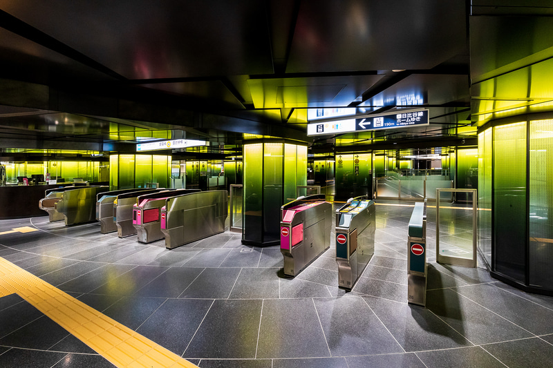 銀座線改札口。ラインカラーとなるレモンイエローの光柱で彩られる。天井まわりの改修により頭上高は2.1mから2.2～2.3m程度にアップしている。