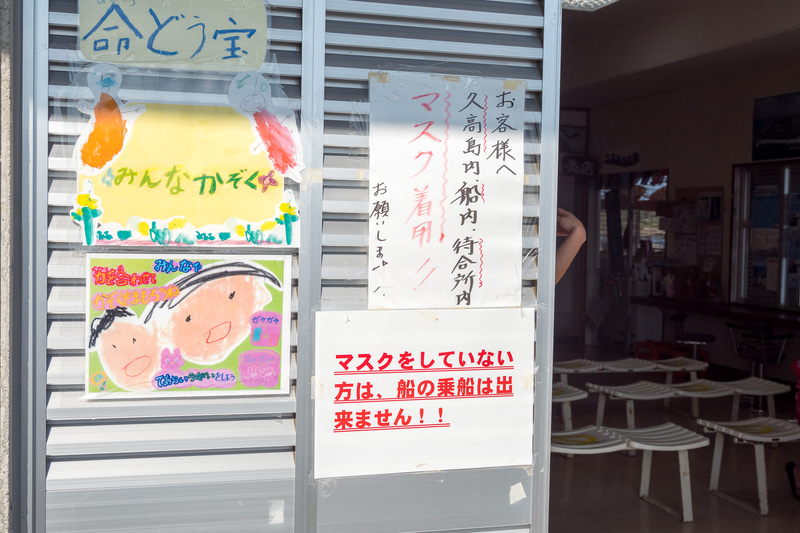 チケット売り場や待合所のほか、お土産物屋さんもある安座真港のターミナル施設。子供たちによる新型コロナへの注意喚起のポスターを掲示している