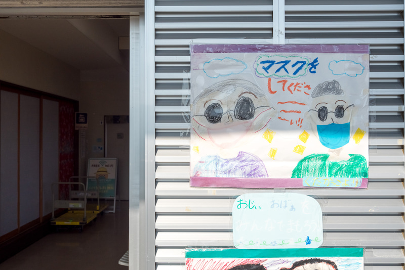 チケット売り場や待合所のほか、お土産物屋さんもある安座真港のターミナル施設。子供たちによる新型コロナへの注意喚起のポスターを掲示している