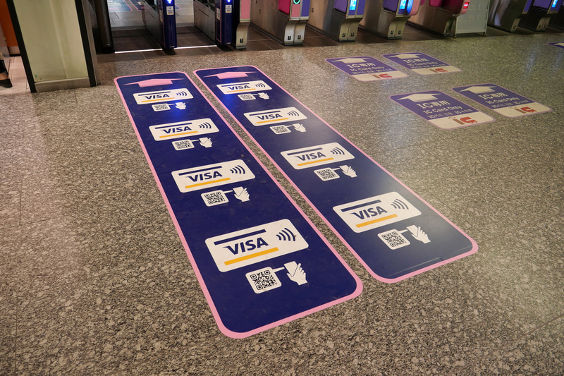 専用自動改札機の手前床には、Visaのタッチ決済と南海デジタルチケットに対応することを示す案内サインを貼り出す