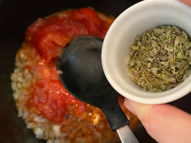 ホールトマト、オレガノを入れて、トマトを潰しながら炒め煮にします