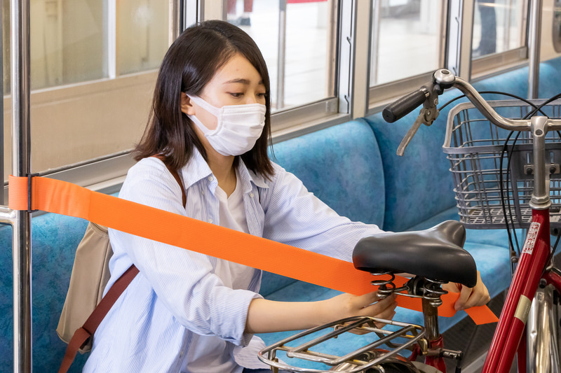 乗車したら空いている席の前で自転車のスタンドを立てる。両面ファスナーになっている固定バンドを自転車のサドルなどに取り付ける。移動中は倒れないようにサドルやハンドルを押さえる