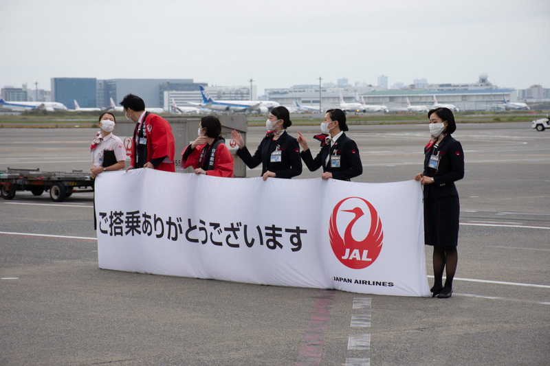 駐機場ではスタッフが横断幕で初便を見送った