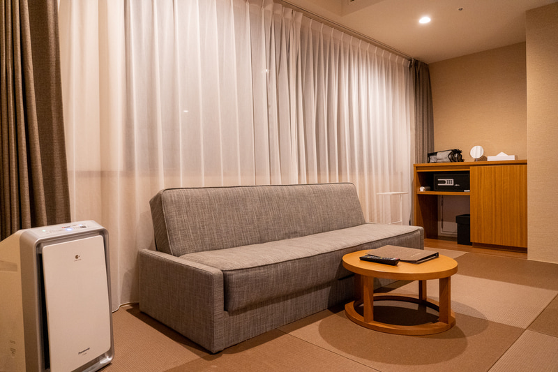 窓側にはロングソファとラウンドテーブル。空気清浄機も