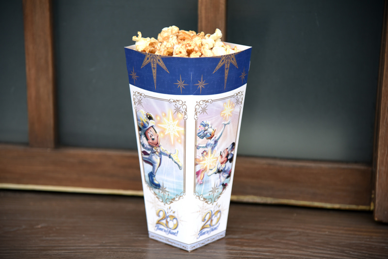 「ポップコーン、レギュラーボックス（キャラメル味）」は箱を閉じるとミッキーマウスたちが手にする光のデザインが現われる
