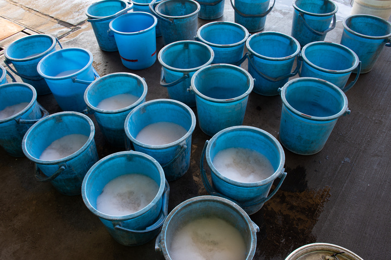 洗浄は洗剤、ブラシやモップ、放水機を使って、人の手で行なう