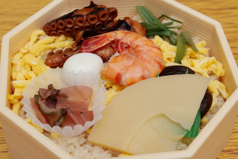 折り詰めにぎっしり詰められたたこ飯の上に、いろいろな具材が盛り付けられている