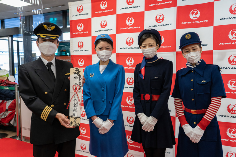 お札を受け取った岸機長と歴代制服着用のCA