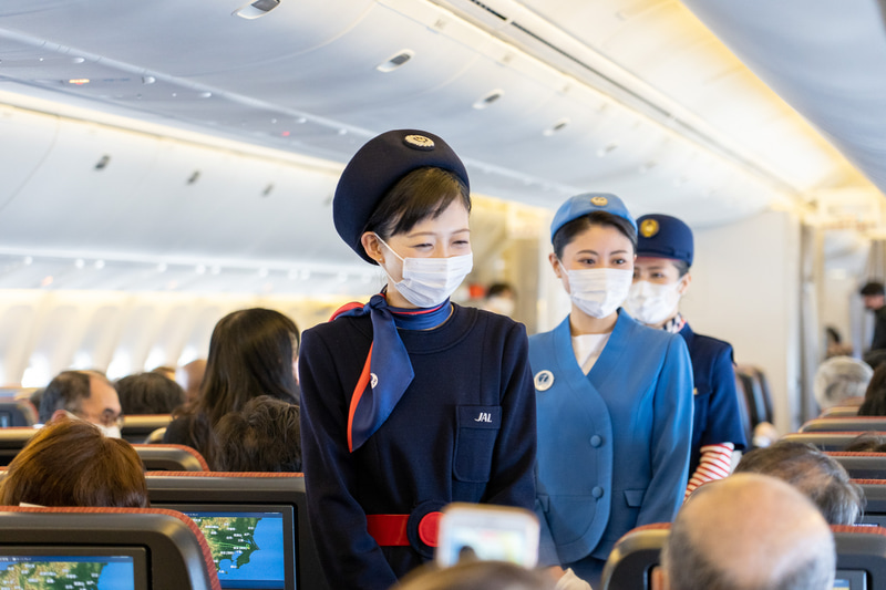 写真撮影に応じるJALの歴代制服を着用したCA。個人的に好きなのはストライプの袖がポイントに森英恵さんデザイン（写真右）。1977～87年に使われたものだそう