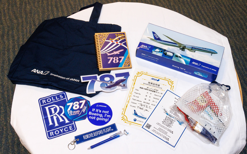 参加者に配られた記念品。右のビニール巾着はエコノミー系の参加者に配られたスナックバッグ。ビジネスクラスの参加者には機内で軽食が用意された
