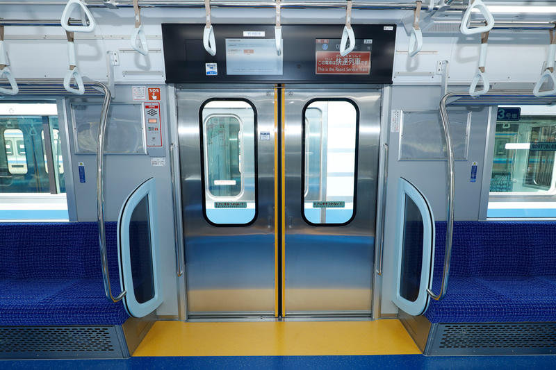 側扉の内側と、側扉付近の床面はイエロー。これは注意喚起色で、デザインというよりも、バリアフリー上の要請によるもの。写真の側扉上部には車内防犯カメラはなく、反対側の側扉の上に付いている