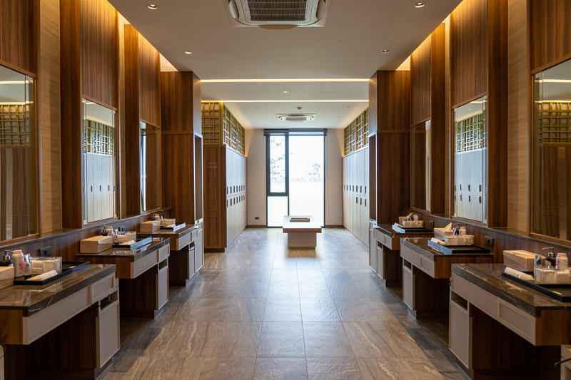 高級感ある木目調のロッカールーム（男性用）。洗面台もシャワーブースも広くてキレイ