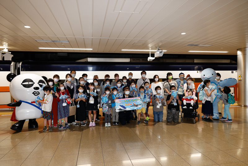 成田空港駅の駅長に、京成パンダとホヌの着ぐるみが加わり、参加者一同と記念撮影。