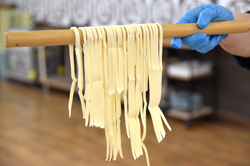 うどんの暖簾。麺棒に掛けてカットの仕上がり具合をチェック