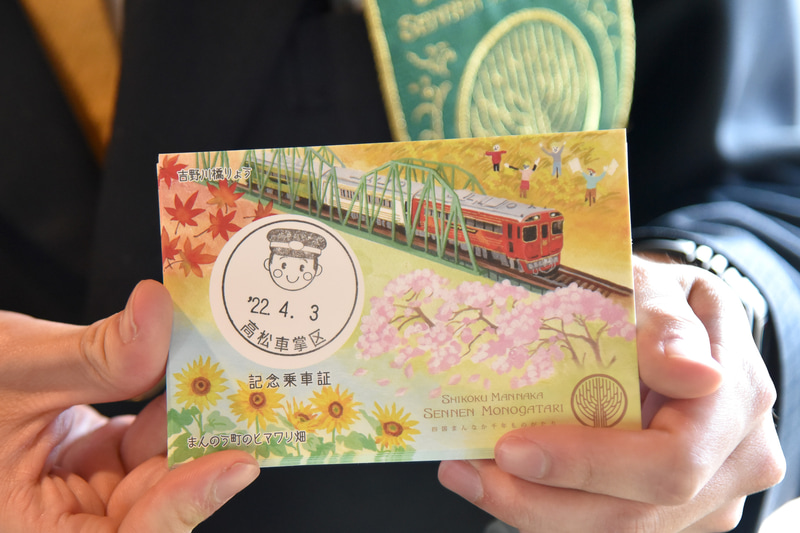 窓から見える桜やカカシなどが描かれた記念乗車証を車掌が手渡してくれた