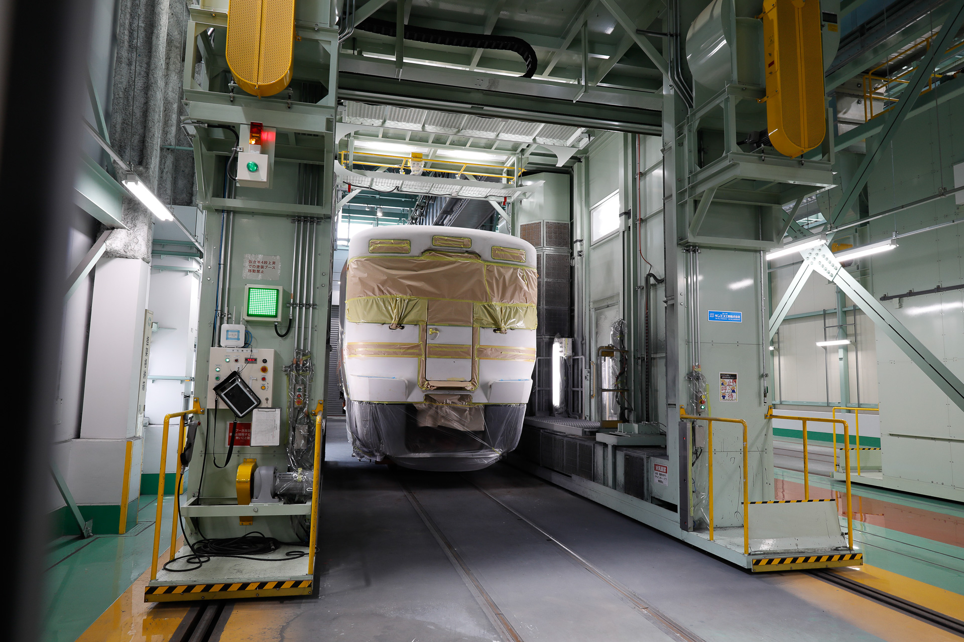 自動塗装ロボットの全景。可動式アームの先端に塗料を噴射するガンが付いており、それを取り付けた門型の装置全体がレールに沿って前後に移動する