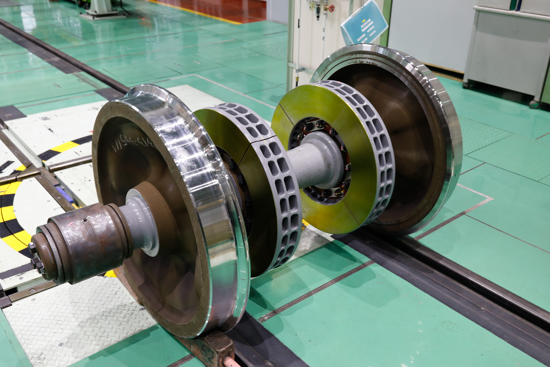 これが輪軸。通常は車軸と左右の車輪が一体になって回転しているが、検修の際には車輪を引き抜く。車軸の外径よりも、車輪の中心にある穴の内径の方が少し小さくなるように作られていて、100tの荷重をかけて押し込む（圧入する）ことでガッチリはまる