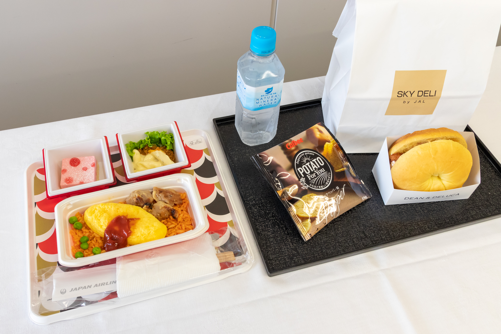 左が従来の機内食。手前のメインディッシュのプラスチック容器と、写真には写っていないがそれを覆っているアルミホイル、サイドディッシュの透明フタが使い捨て。新機内食はカトラリーがいらないので機体の軽量化も図れる。ちなみに食事の量自体はほとんど変わっていない