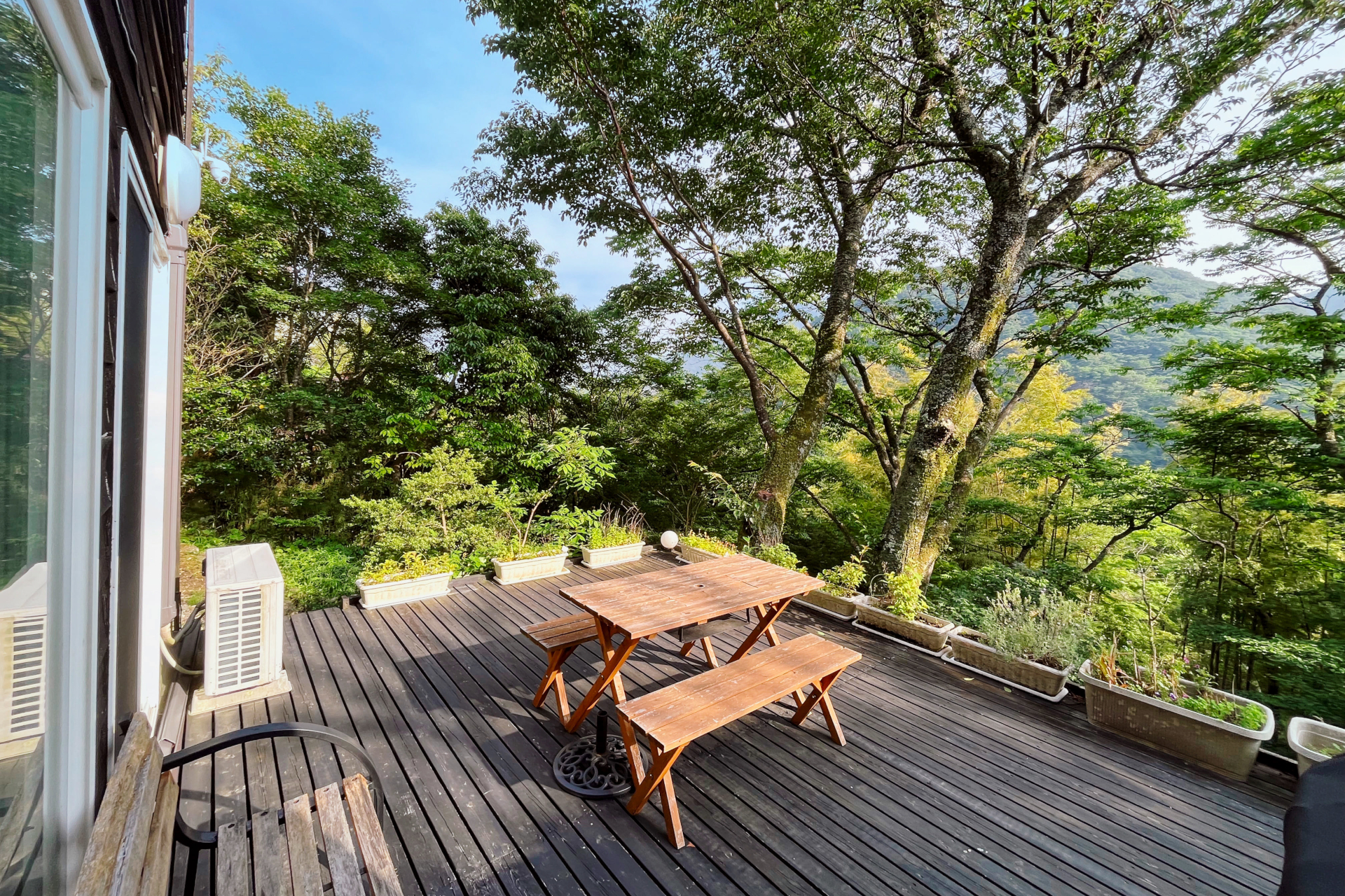 高台に設けられた広いウッドデッキ。アウトドアテーブルで食事したりベンチでくつろいだりして過ごせる