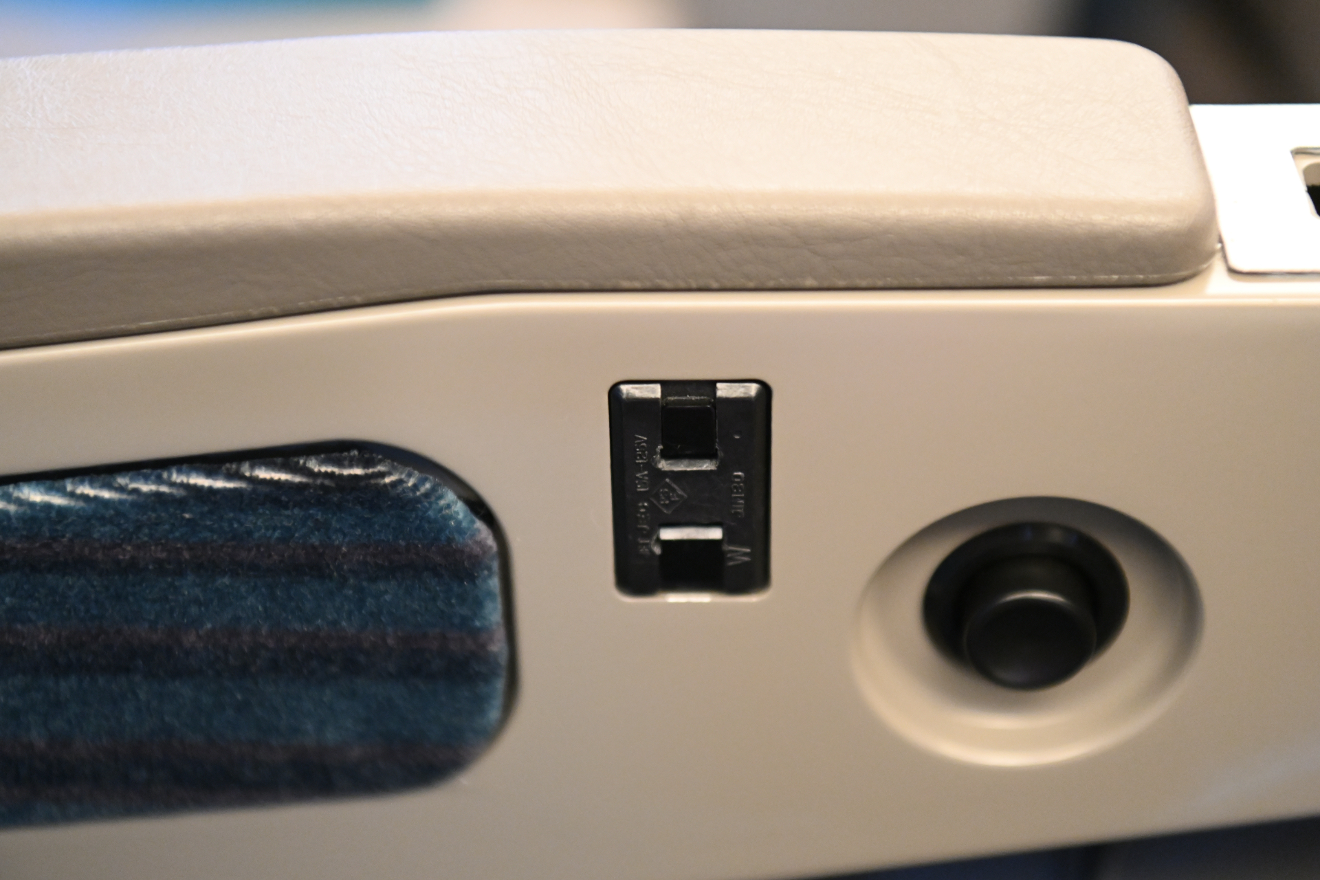 普通指定席の肘掛け下にあるコンセント。シートのファブリックは寒色系の色