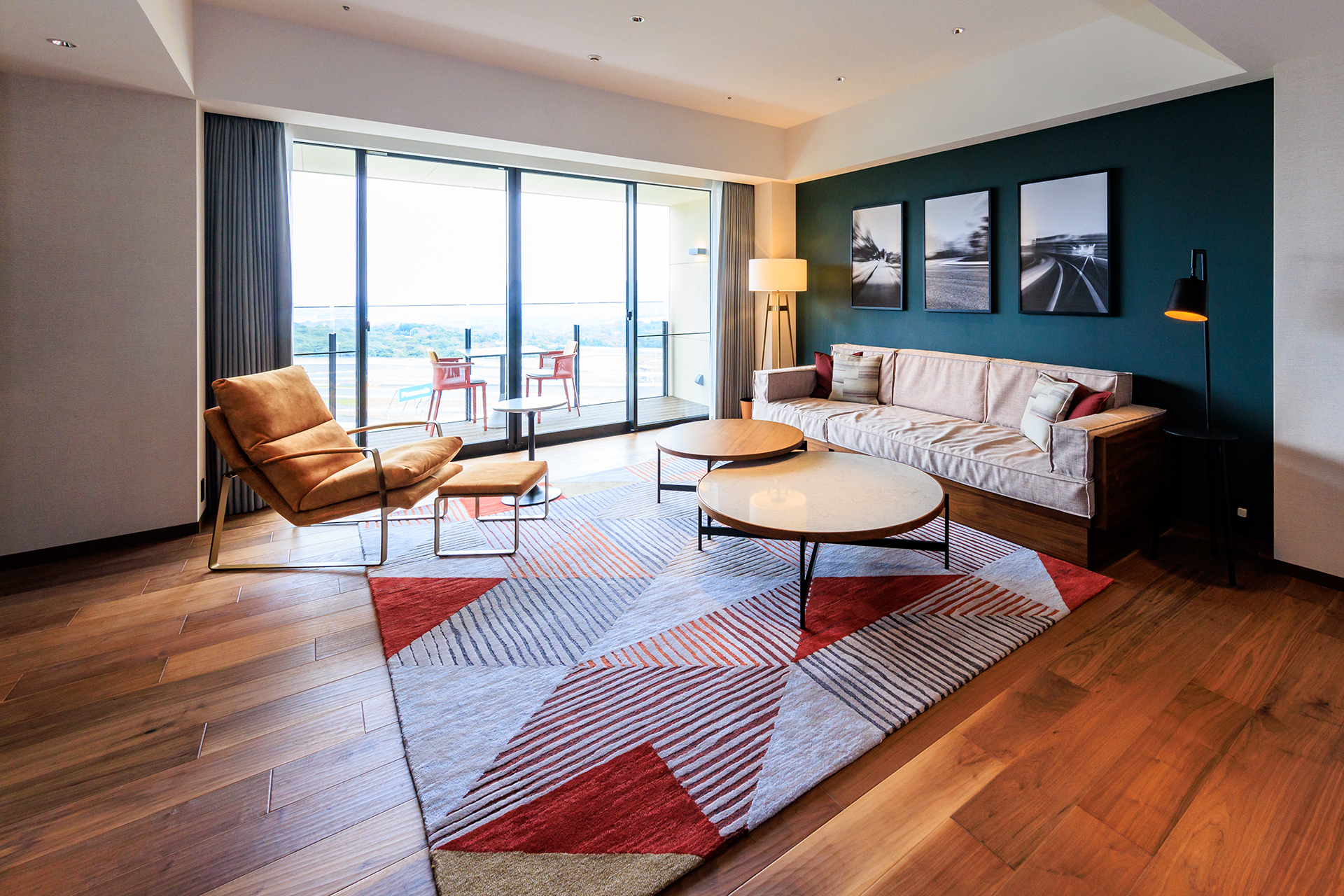 広い室内にはゆったりとしたソファー、外を見ると広いバルコニーとサーキット。贅沢すぎる空間が広がる