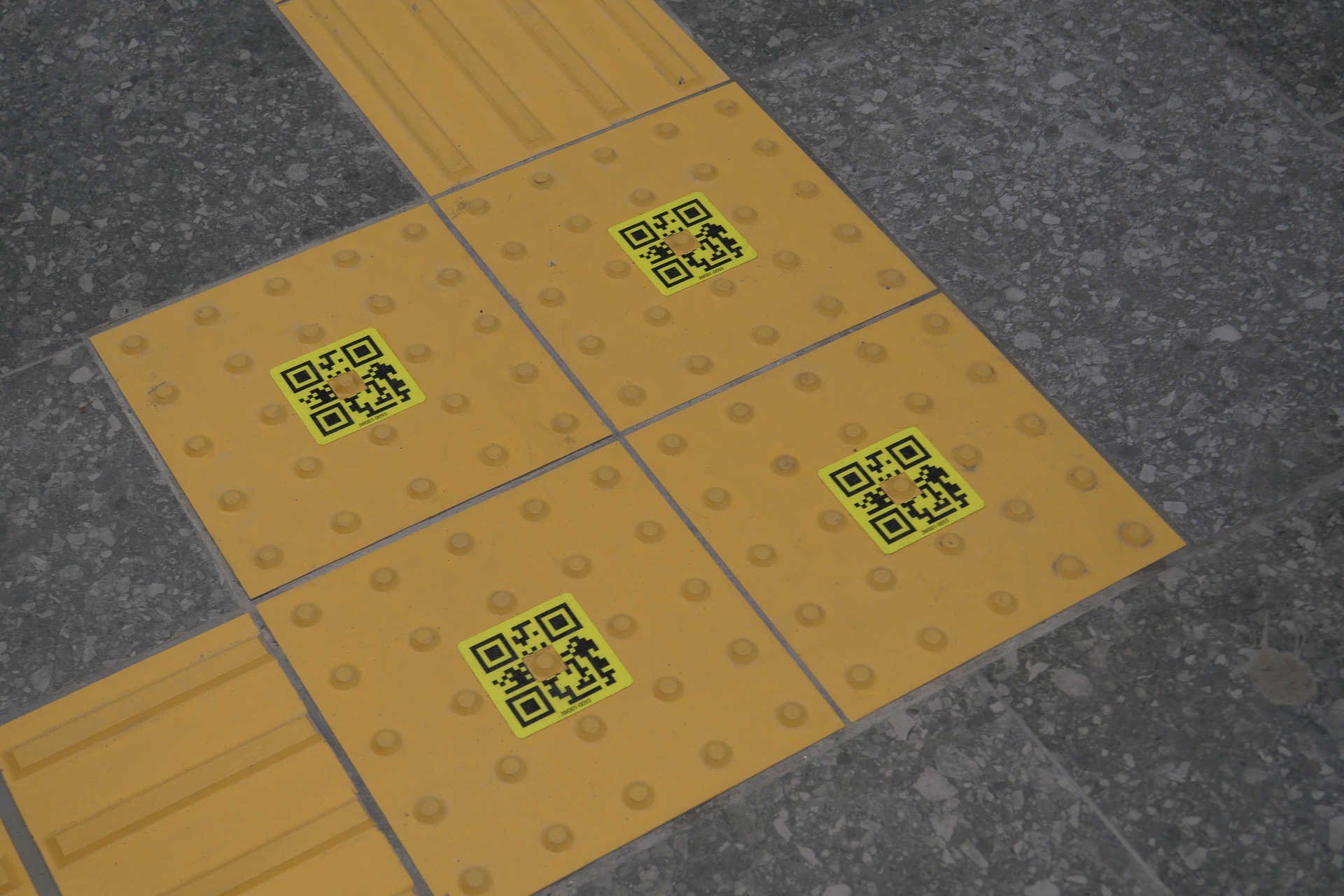 点字ブロックの角や分岐点にQRコードを埋め込み、スマートフォンアプリで読み取ることで目的地までの移動をサポート