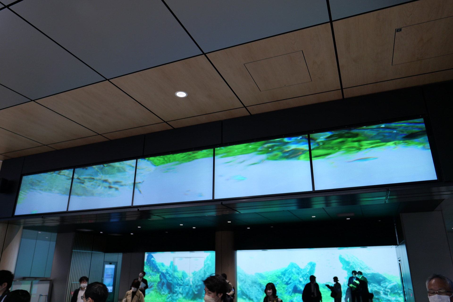 待ち合いエリア入り口上部のサイネージと、奥の壁のプロジェクションマッピングで環境映像を表示