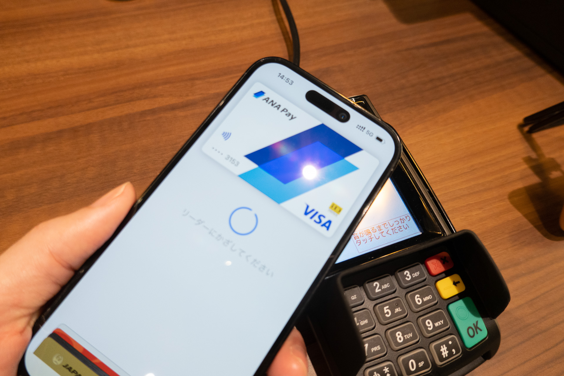 Apple PayでANA Payを選んで生体認証を行ない、レジの端末にかざす