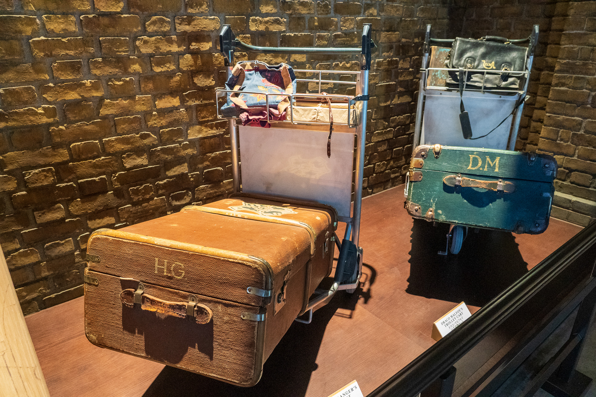 手荷物カートを展示。トランクには「H.G」や「D.M」などイニシャルが