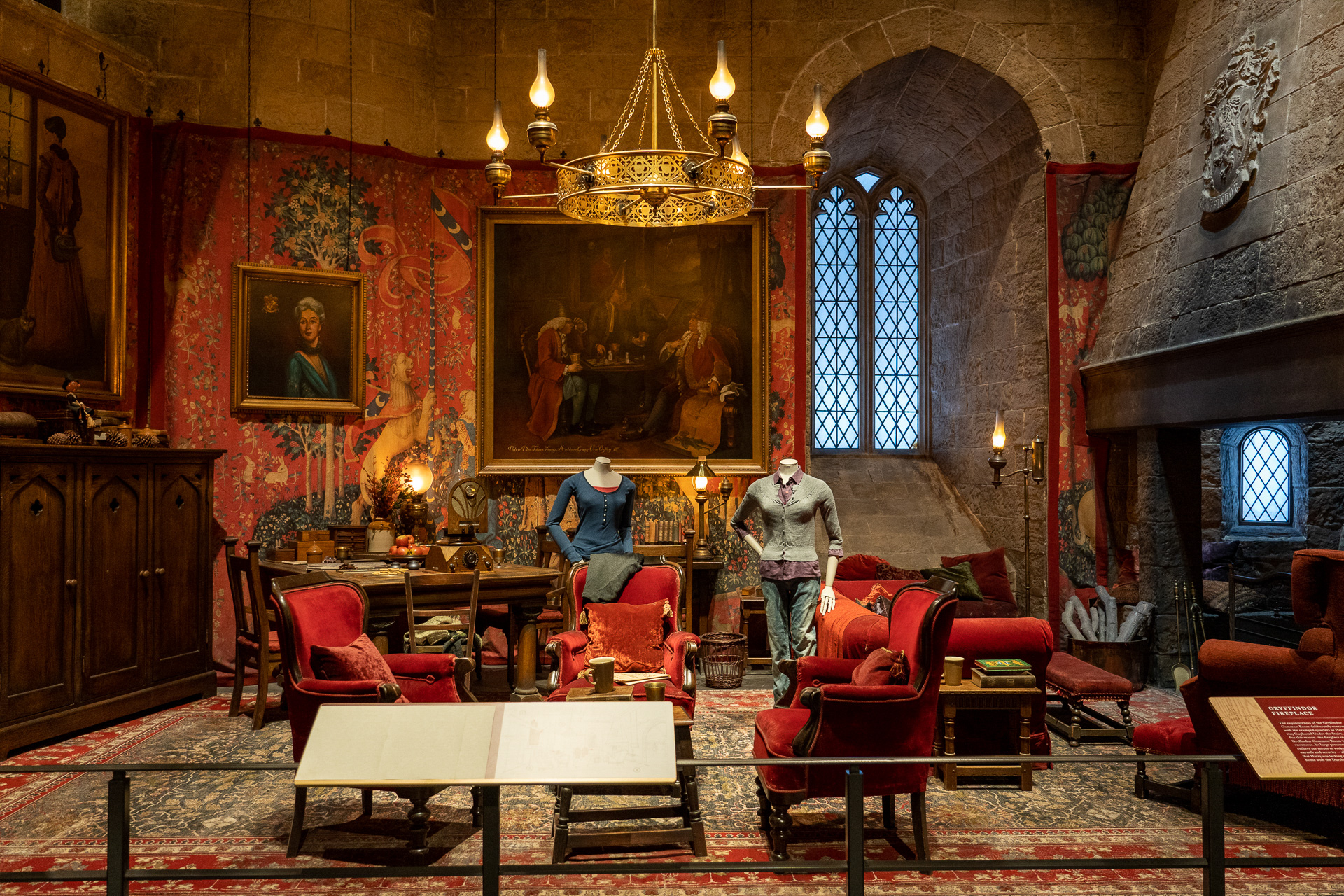 貴婦人と一角獣が描かれた赤いタペストリーが壁に掛かるグリフィンドール談話室のセット。ハーマイオニーの衣装マネキンも