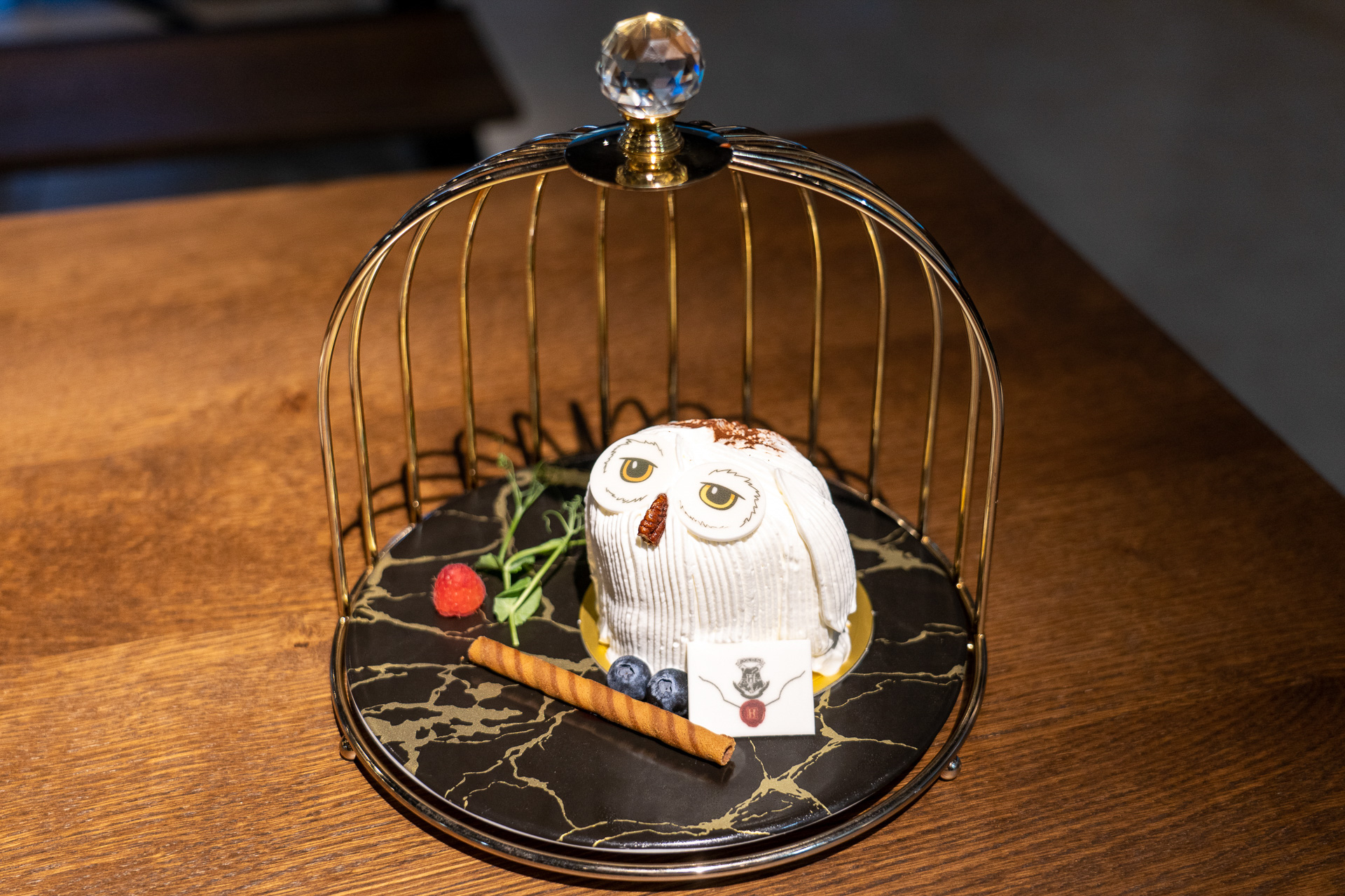 鳥かご型のケーキスタンドで提供されるヘドウィグケーキは1500円。封筒のクッキーが添えられている。最初のひと口をどこから食べたらいいのか迷いそうだ