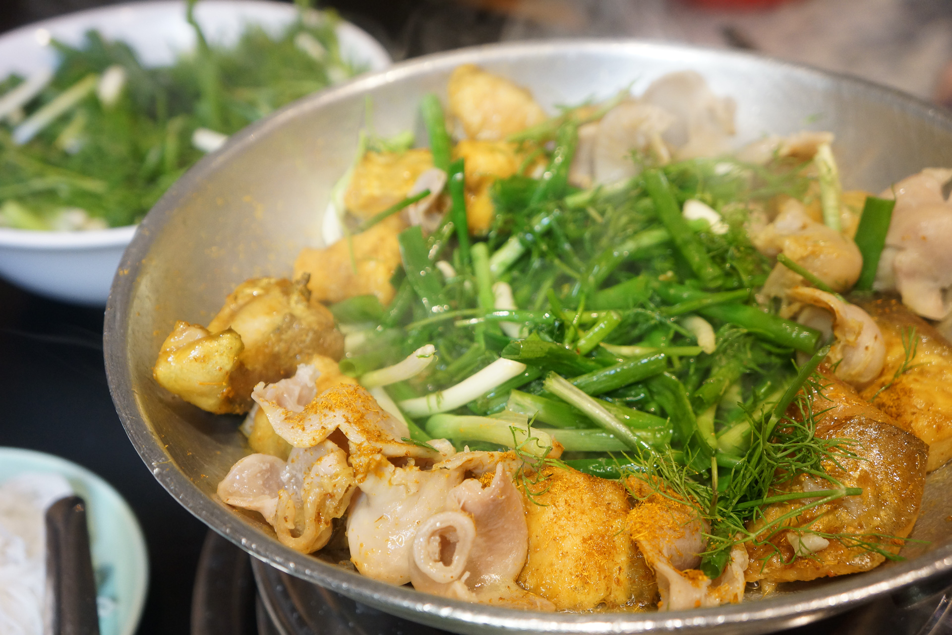 ハノイ名物料理チャーカー、ターメリックなどに漬け込んだ白身魚を、たっぷりのネギとディルで揚げ焼きに。専門店があるほど人気