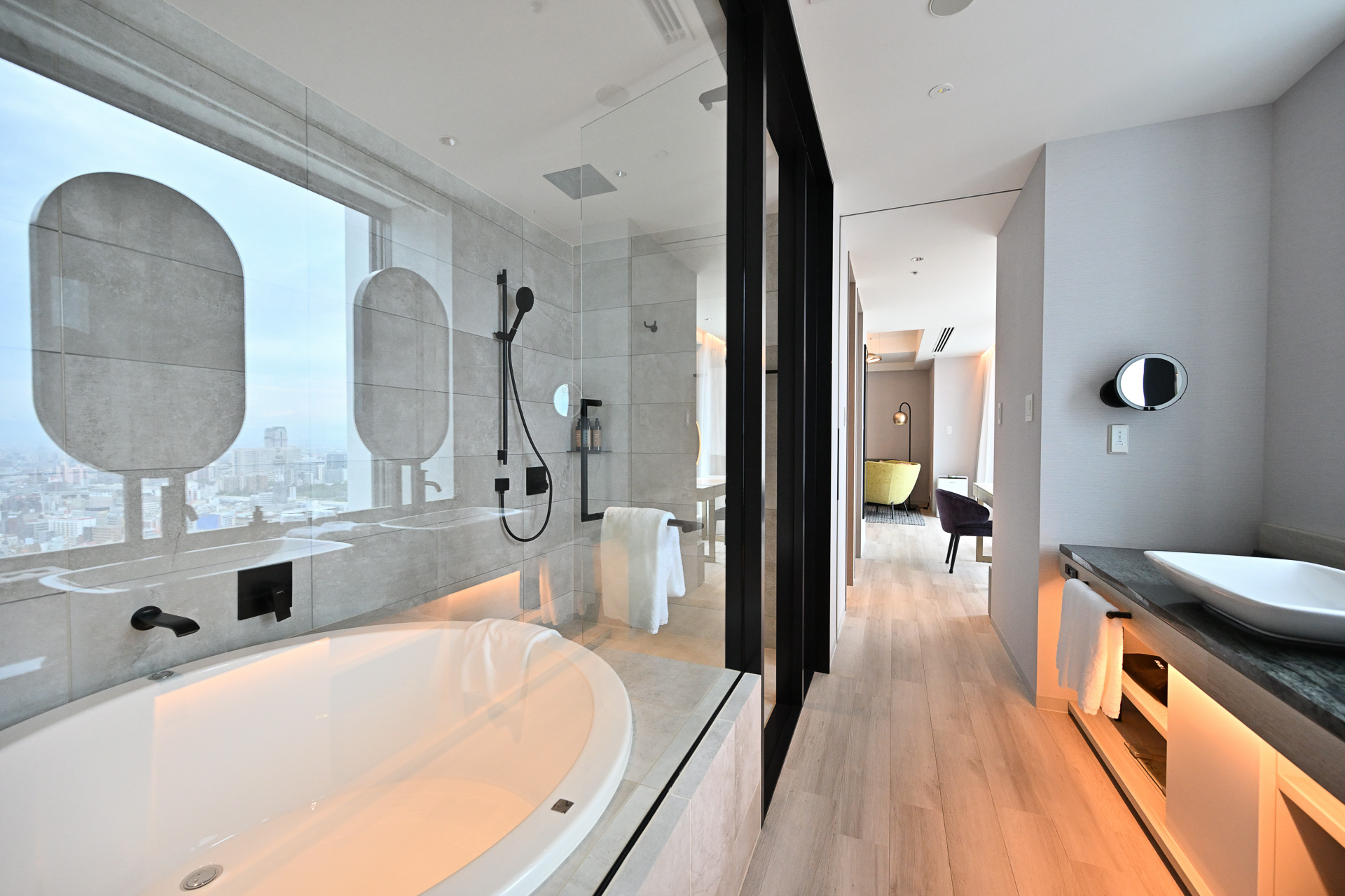 長い通路沿いに設置されたガラス張りのバスルームと洗面台