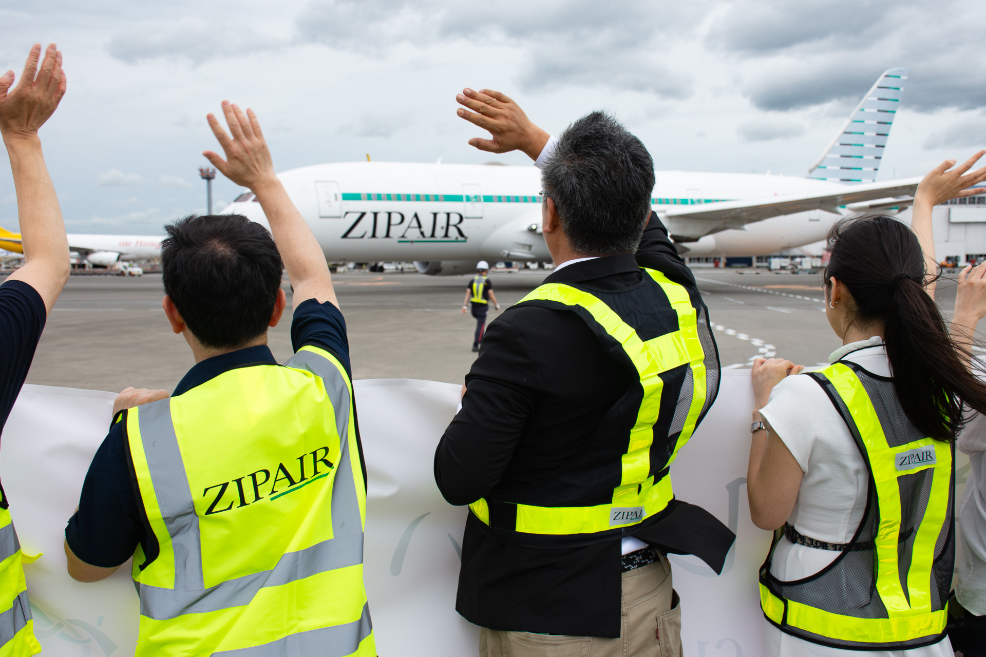 横断幕とともに手を振って見送り