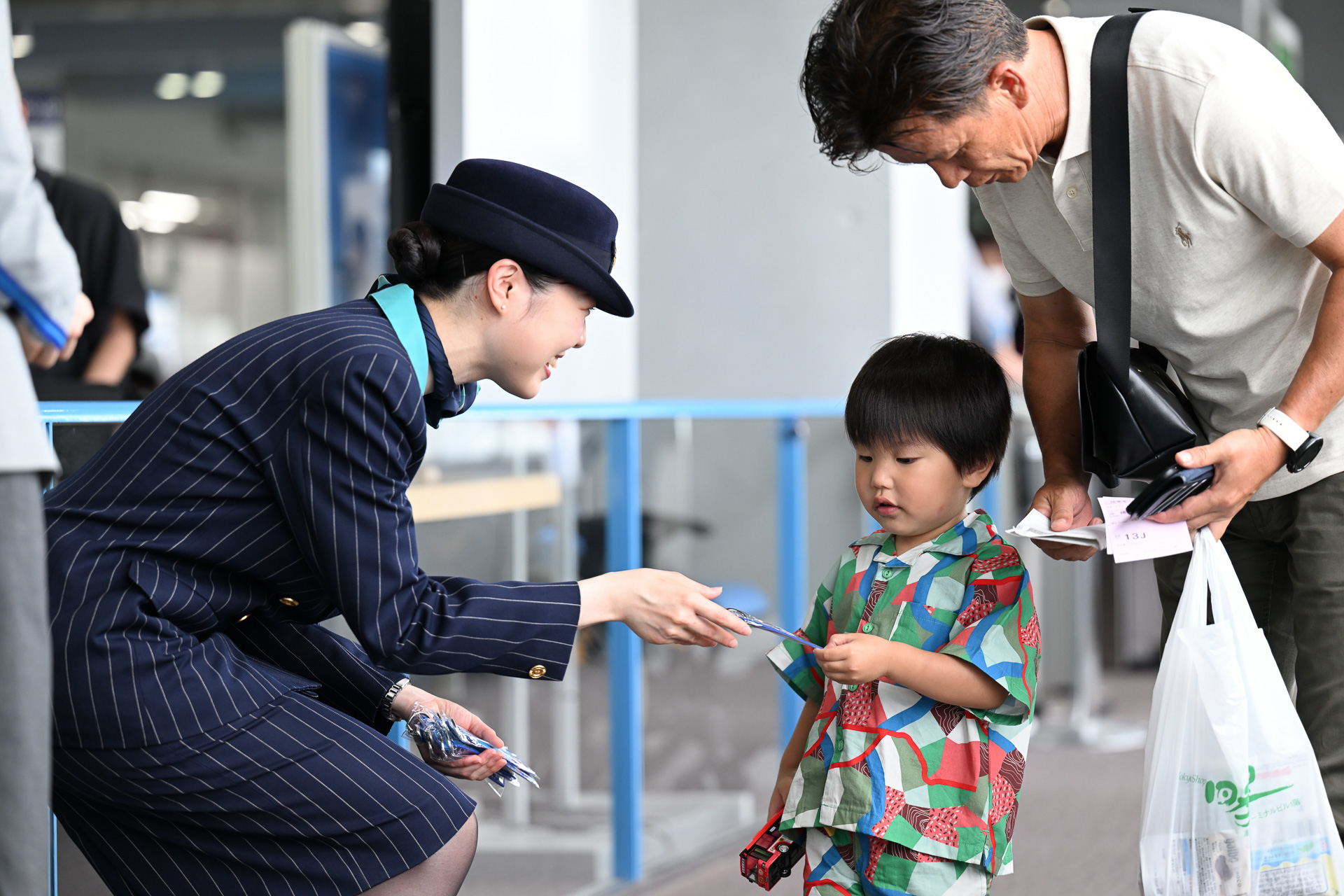 ANA那覇便の搭乗客に記念のフライトタグキーホルダーを手渡すANAの客室乗務員