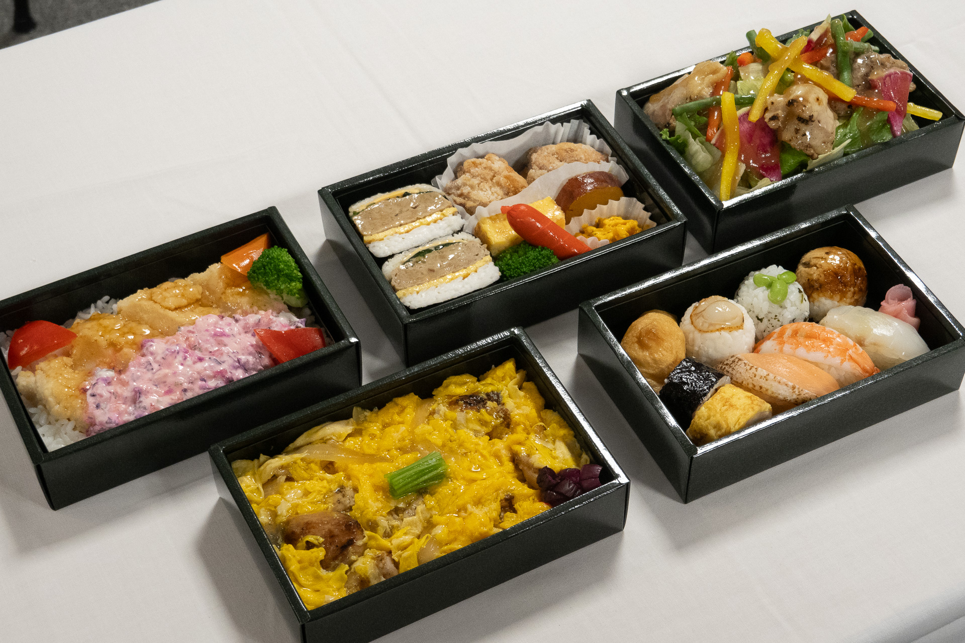 左手前から「ふわとろ卵の炭火焼き親子丼」（1600円）、「寿司ものがたり」（2000円）、「チキン南蛮丼 ～あけぼのタルタル添え～」（1600円）、「おむすび弁当」（1500円）、「チキンと紅芯大根の野菜たっぷりサラダ ～バルサミコドレッシング～」（1500円）