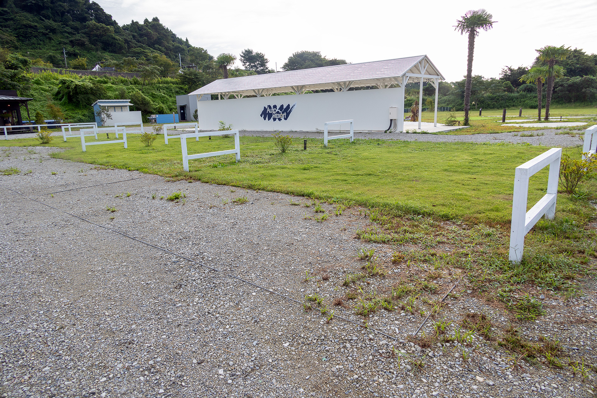 ゲートエリアのG8スペース（配置図参照）から管理棟方面を見る。芝生の前にロープで仕切られているのが素のスペース専用の駐車エリア。芝生内にクルマを乗り入れないでテントを張りたい場合はここに駐める。この駐車エリアは「バンエリア」「ペット同伴エリア」を除くすべてに設定されている