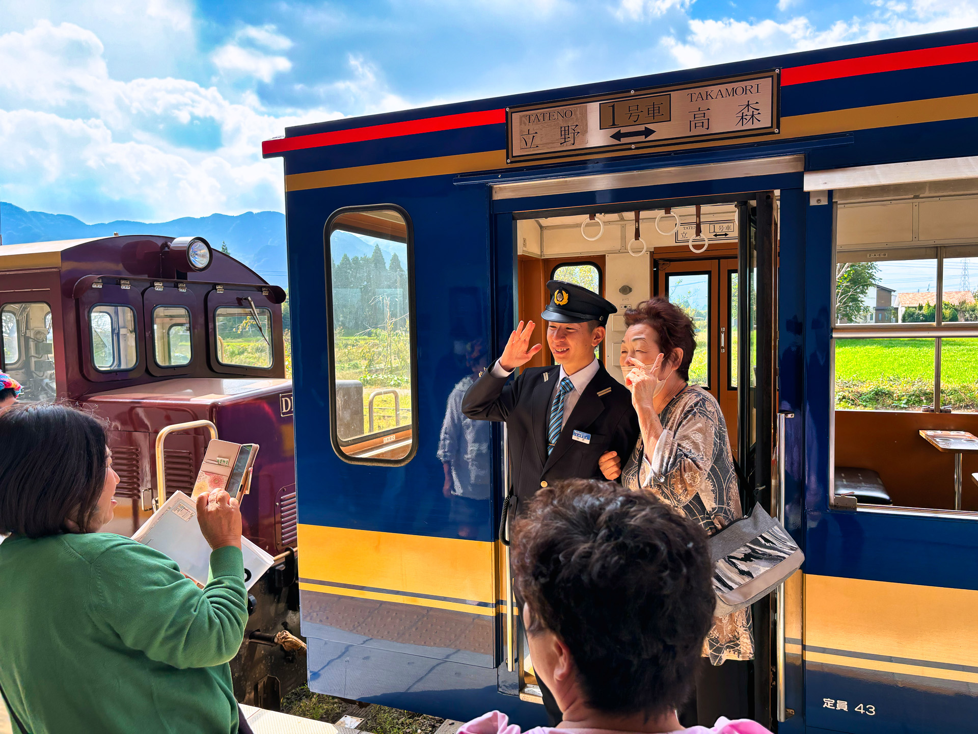 いよいよトロッコ列車が高森駅のホームに入線。スマートフォンのシャッター音が響いた。早速車掌との撮影会が始まった