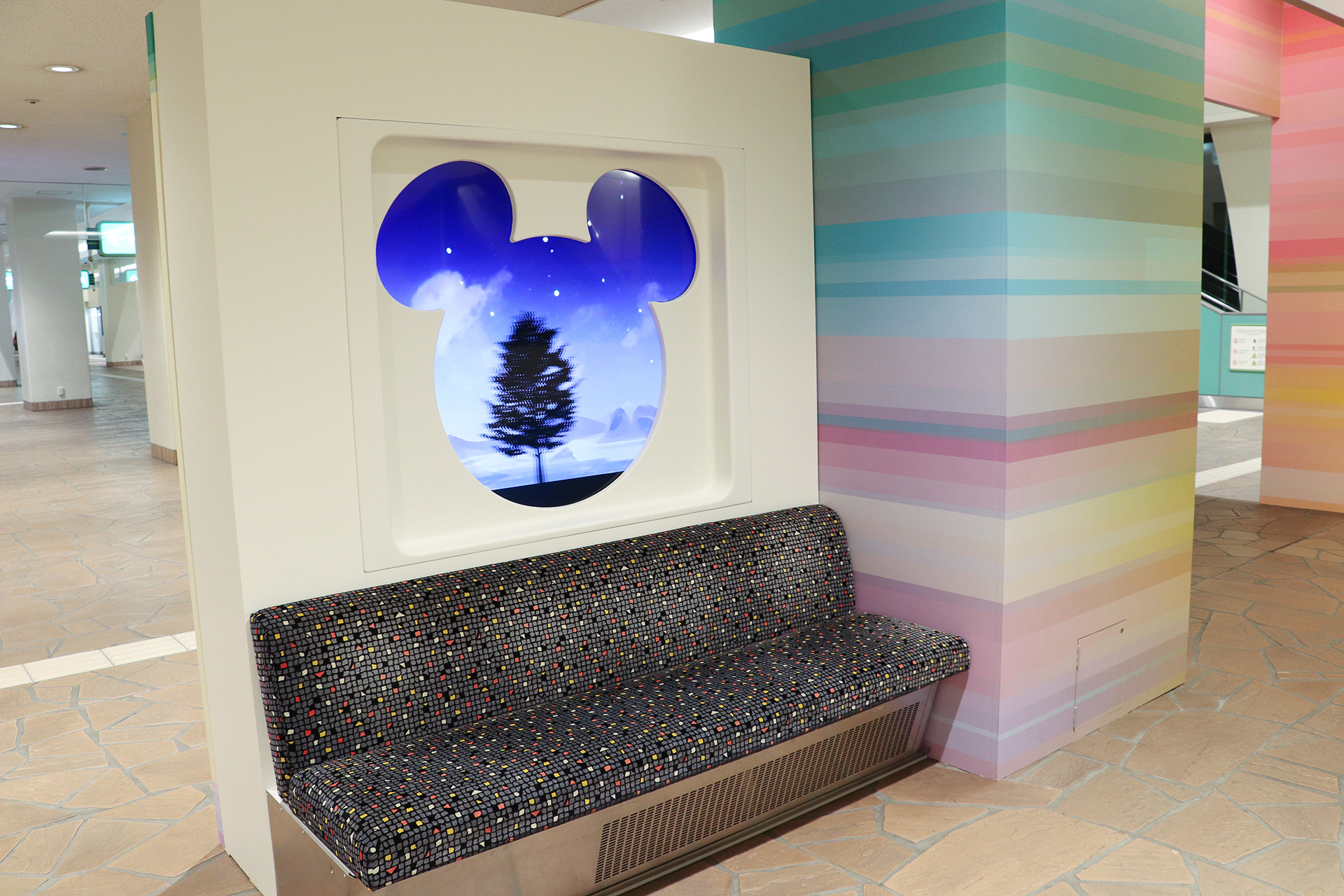 座席とミッキーマウス形の窓の展示。風景が走行中のように動く