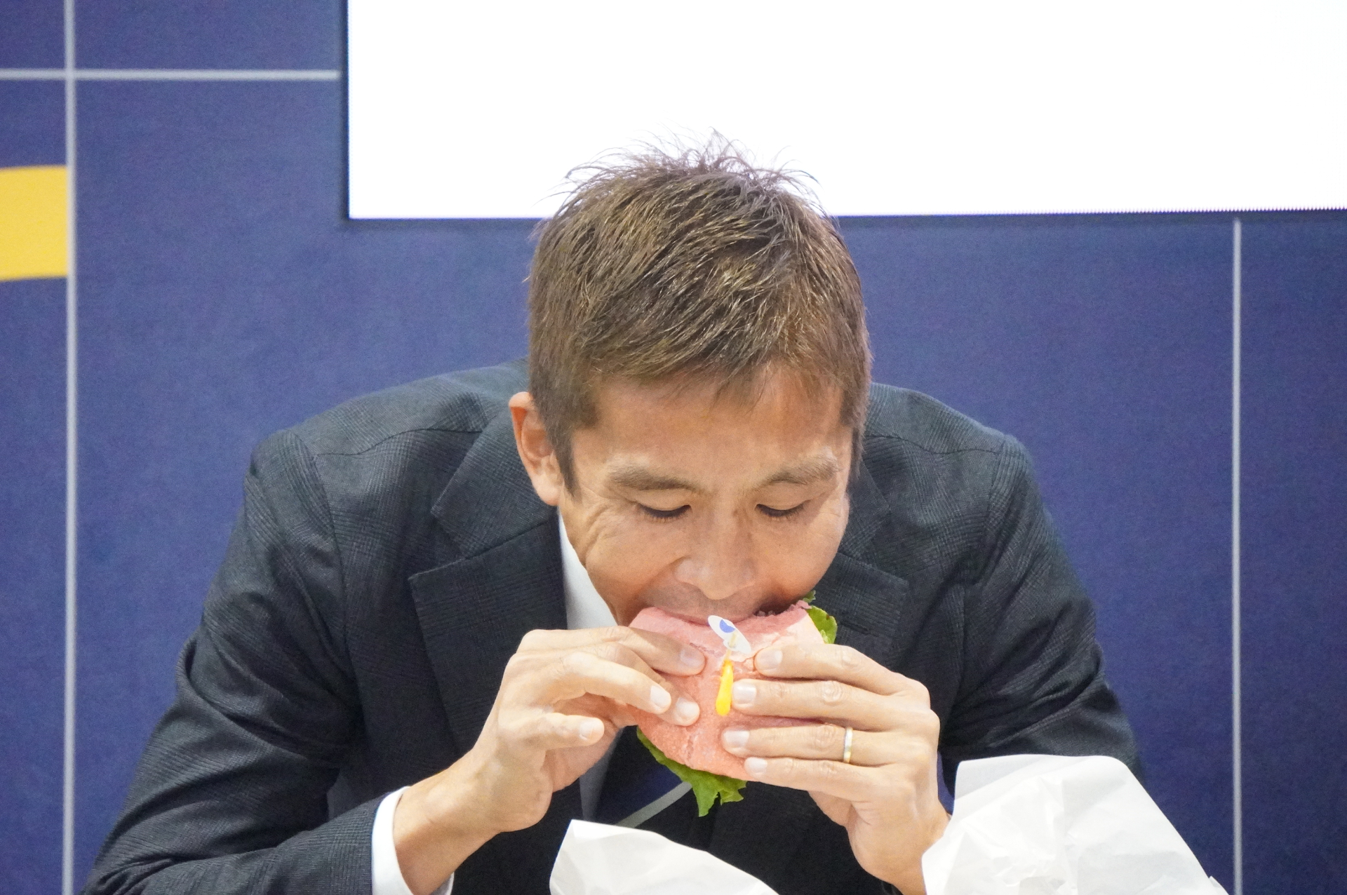 カフェ＆バーで提供される「なでしこエビ勝つバーガー」を試食する稲本さん