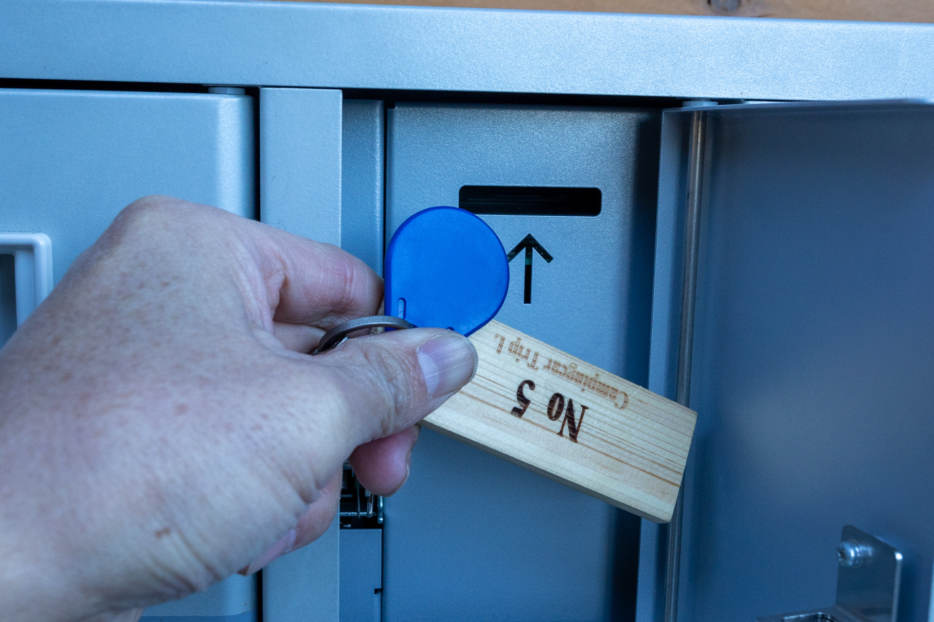 チェックアウト時は青いフダを穴に挿し込むとシステムは「チェックアウト」と判断する。キーにはキーホルダーとして木札が付いていて、間違ってこれを挿す人もいるが、それではチェックアウトと認識されない。すると延長料金が掛かってしまうこともあるので注意を