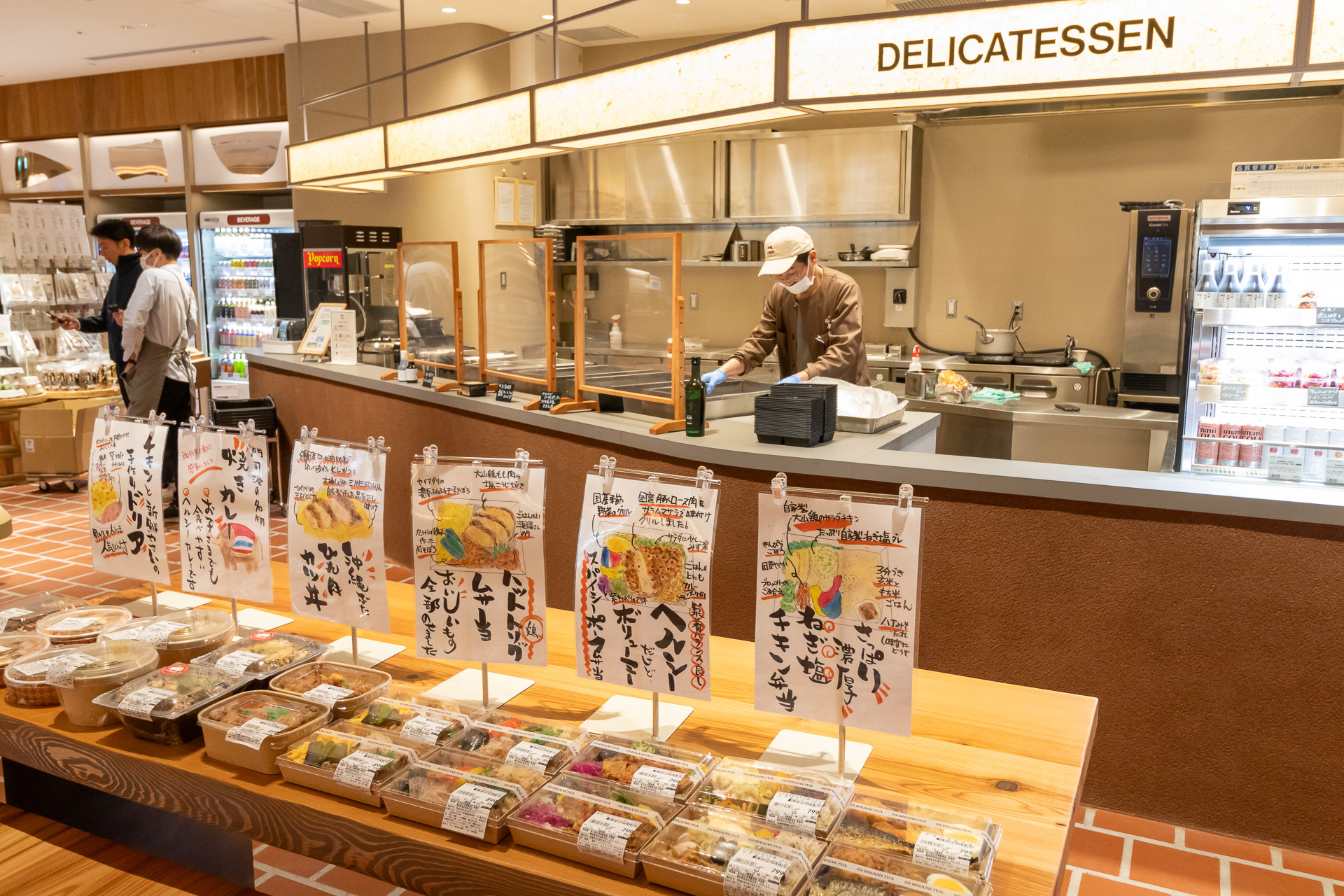 弁当や総菜のほか、ソーセージやチーズといったオードブルも取り扱っている。お酒はウイスキーとワインを中心として数多くのボトルが並ぶ