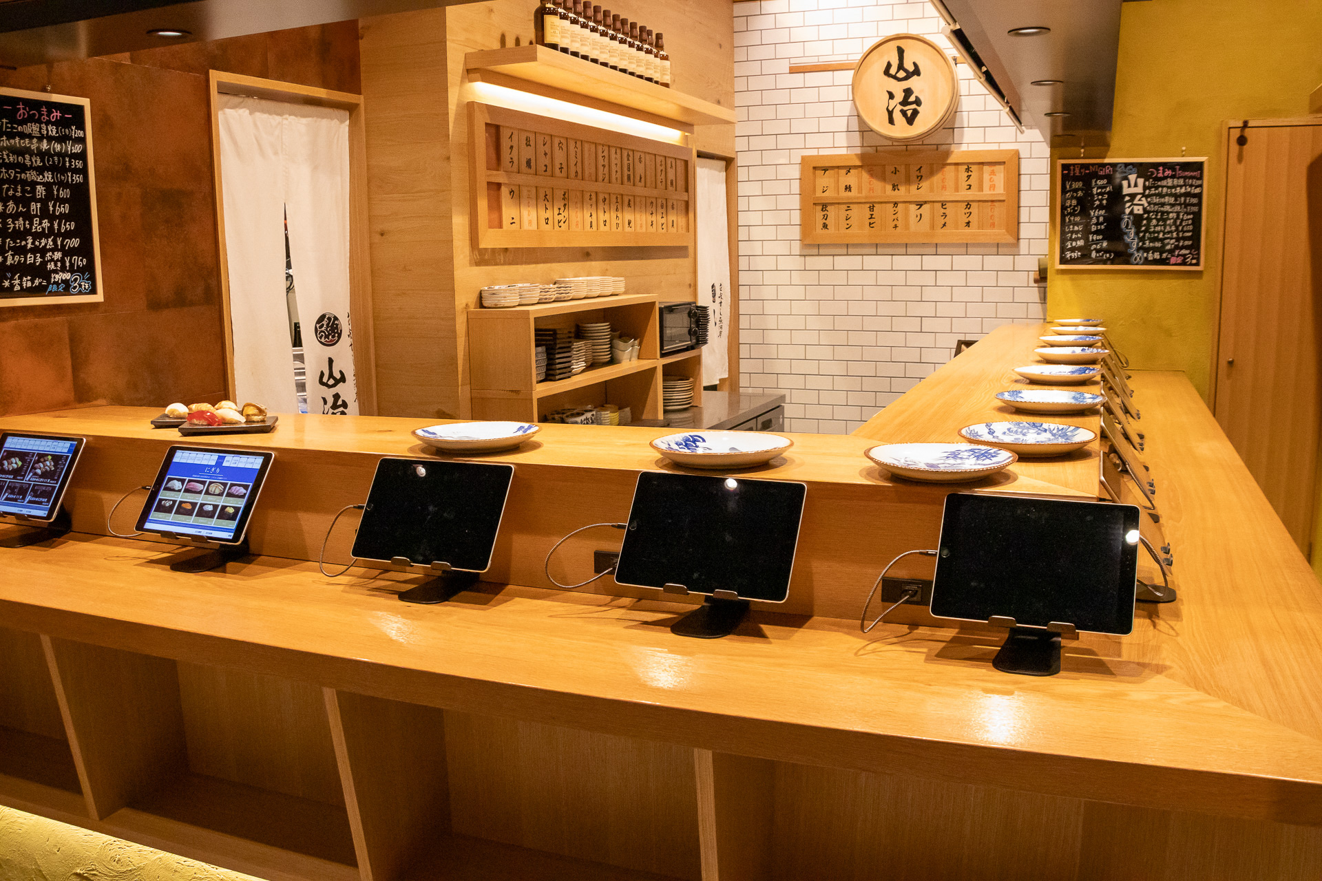 「立喰すし魚河岸 山治」はサクッとお寿司が楽しめる手軽さが魅力。外国人でも手軽にオーダーできるように手元にはタブレット（日・英対応）を用意している